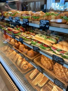 a display case in a bakery filled with lots of different types of sandwiches and pastries