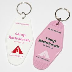 two pink and white key chains with camp bachelorette tags attached to them, on a white surface