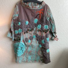 a shirt hanging up on a wall next to a coat hanger with an orange and blue flower design