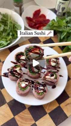 sushi rolls on a white plate with chopsticks and salad in the background