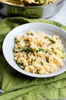 a white bowl filled with rice and asparagus on top of a green towel