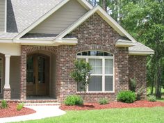 a brick house with green grass and trees