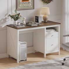 a white desk with a computer on top of it next to a lamp and flowers