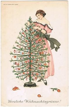 a woman in a pink dress standing next to a christmas tree with decorations on it