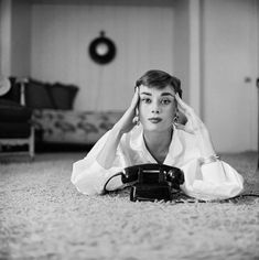 a black and white photo of a woman laying on the floor with her head in her hands