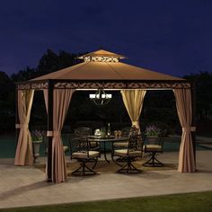 an outdoor gazebo with curtains and lights on it at night near a swimming pool