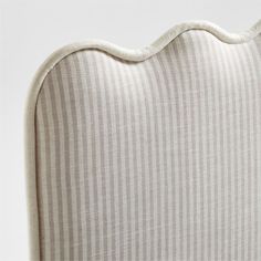 an upholstered headboard with white and grey stripes on the back, in front of a white background