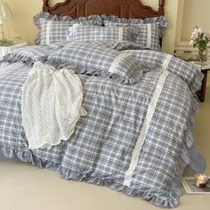 an unmade bed with blue and white plaid comforter, pillows and blankets on it