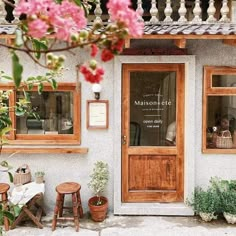 an outside view of a restaurant with flowers and potted plants on the front porch