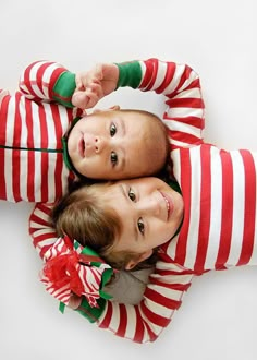 two young children laying on top of each other wearing matching striped pajamas and holding their hands in the air