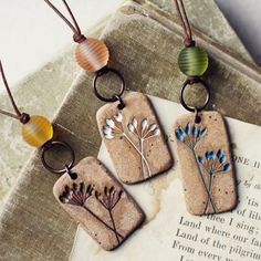 three necklaces with flowers on them sitting next to an open book