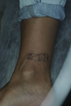 a small elephant tattoo on the foot of a person's leg, with two elephants behind it