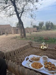 a person sitting at a table with plates of food in front of them and a teapot on the side