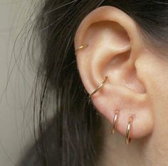 a close up of a person's ear with two gold hoops on it