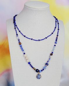 Handmade beaded necklace inspired by palm fronds against the blue sky. Long (34") clasp-free design allows for easy layering with other necklaces. This necklace features a stone pendant and beads of lapis lazuli, blue tiger's eye, wood, and millefiori glass. Lapis Lazuli Blue, Handmade Beaded Necklace, The Blue Sky, Bead Sewing, Palm Fronds, Handmade Beaded Necklaces, Blue Tigers Eye, Wood Necklace, Blue Wood