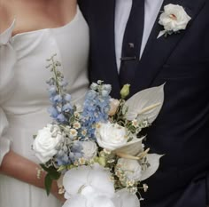 the bride and groom are posing together for a wedding photo with flowers in their bouquet