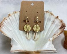 Elevate your beach style with these stunning Hammered Disc and Cowrie Shell Earrings. This beautiful pair is handcrafted with gold plated brass disc beads and natural cowrie shells, making them versatile enough to wear every day and suitable for any occasion. The lightweight design and easy to wear leverback hoops make them a comfortable choice for all-day wear. The earrings measure 5 cm in length, with the 24K gold plated hoops measuring 15 mm in diameter and 1.6 cm in length. These statement e Gold Drop Earrings For Vacation, Beachy Gold Jewelry For Vacation, Beachy Gold Vacation Jewelry, Handmade Dangle Hoop Earrings For Vacation, Gold Dangle Earrings For Beach Season, Handmade Hoop Earrings For Summer Vacation, Handmade Hoop Jewelry For The Beach, Handmade Earrings For Beach Season Gifts, Handmade Earrings For Beach Vacation