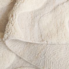 an up close shot of the texture of a white and beige blanket on a bed