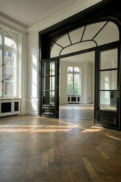 an empty room with wooden floors and black doors