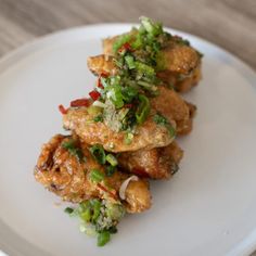 a white plate topped with chicken and veggies on top of a wooden table