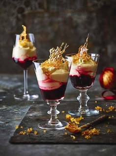 two glasses filled with dessert sitting on top of a table next to an orange peel