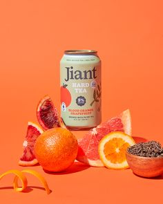 an orange and grapefruit drink next to some sliced fruit on an orange background