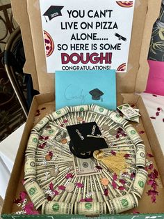 an open box with money in it and a graduation cap on top