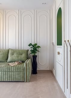 a green couch sitting next to a tall black vase