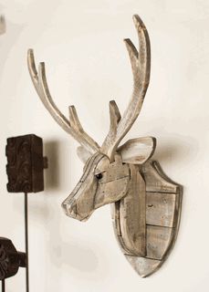 a wooden deer head mounted to the side of a wall next to two sconces