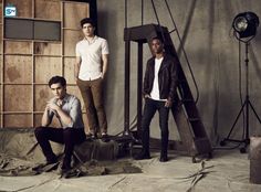 three young men are posing for a photo in front of a wooden wall and ladder