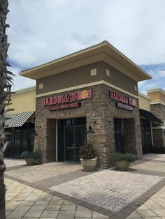 the outside of a restaurant with palm trees in front