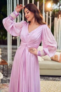 Purple gown featuring bishop sleeves, gathered front knot, and sequin-bead embellishments on the cuffs, Fit: Relaxed Elegant Pink Dress With Elastic Sleeves, Long Sleeve Maxi Dress With Ruched Bodice, Wedding Dresses With Pleated Sleeves And Fitted Bodice, Long Sleeve Ruched Maxi Dress For Wedding, Feminine Long Sleeve Evening Dress, Pink Bishop Sleeve Dress For Evening, Wedding Dress With Pleated Lantern Sleeves, Ruched Bishop Sleeve Dress For Evening, Formal Feminine Dresses With Elastic Sleeves