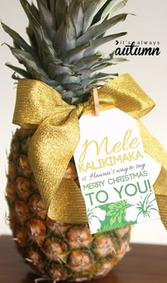 a pineapple is wrapped in gold ribbon and sitting on top of a wooden table