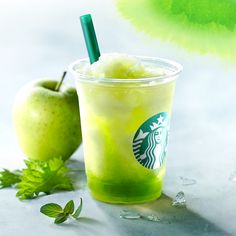 a starbucks drink next to an apple and green leafy garnish on a table