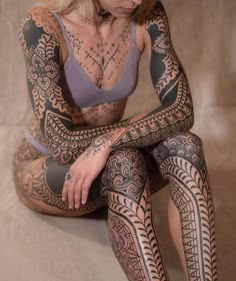 a woman with tattoos sitting on the ground