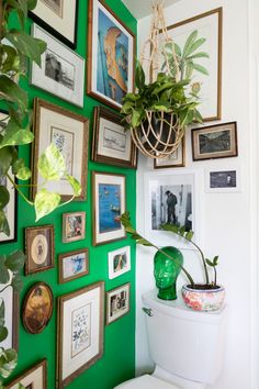 a bathroom with green walls and pictures on the wall, including a potted plant