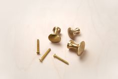 screws and studs are laying on a white surface with some gold colored hardware