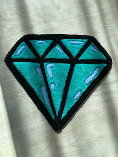 a blue diamond shaped rug sitting on top of a wooden table next to a white curtain