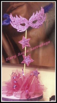 a masquerade cake topper on a stick with pink tulle and stars