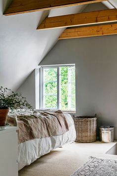 a bed sitting under a window in a bedroom next to a rug on the floor