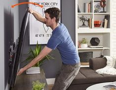 a man standing in front of a flat screen tv next to a plant on top of a coffee table