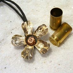 two brass flower pendants sitting on top of a white counter next to a black cord