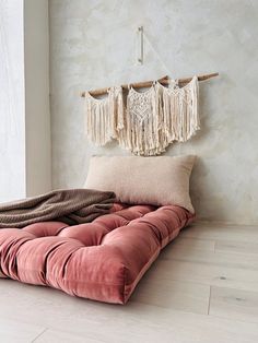 a pink futon bed with fringes hanging from the headboard and pillows on it