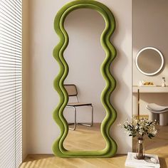 a room with a large green curved mirror in it's center and a vase on the floor next to it