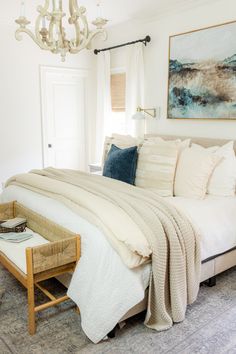 a bedroom with a bed, chandelier and pictures on the wall above it