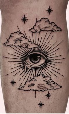 an all seeing eye tattoo on the side of a man's right leg with clouds and stars around it