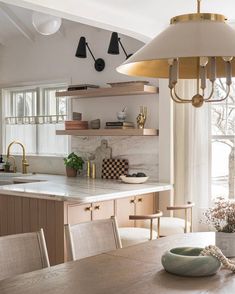 a kitchen with an island table and hanging lights