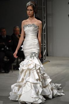 a woman in a white dress walking down a runway