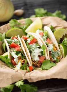 three tacos with lettuce, tomatoes and cilantro