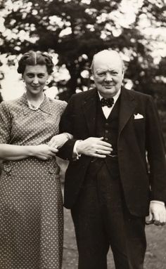 an old black and white photo of two people standing next to each other in front of trees